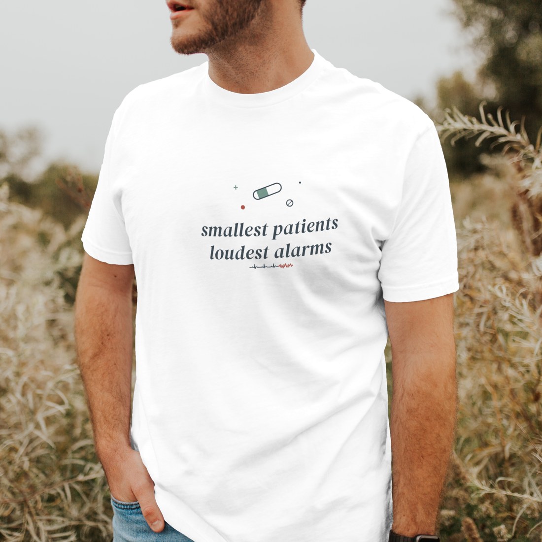 White tee reading “smallest patients loudest alarms” in a clean folded corner shot